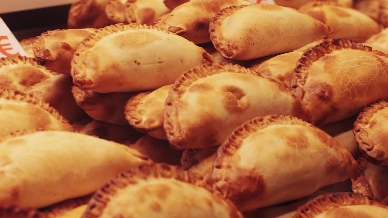 A large stack of freshly baked homemade empanadas beautifully arranged and displayed with a golden, crispy crust