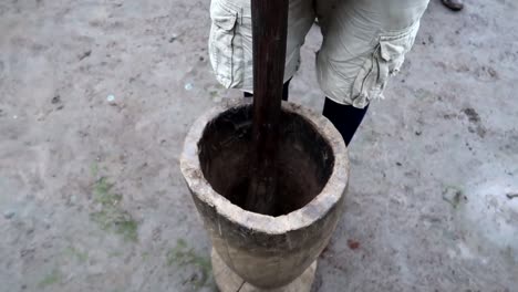 hombre local africano moliendo granos de café arábica con un mortero de madera gigante en tanzania