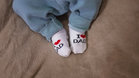 adorable babe's feet in tiny socks. i love you dad socks on the little feet on the grey backdrop. close up.