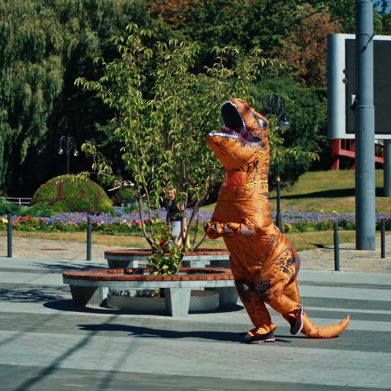 Happy dragon runs outdoors. Person having fun wearing animal costume in the city park. Joyful time.