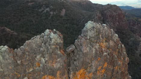 Sunrise-through-amazing-natural-rock-formation-archway,-tall-cliff,-aerial-view