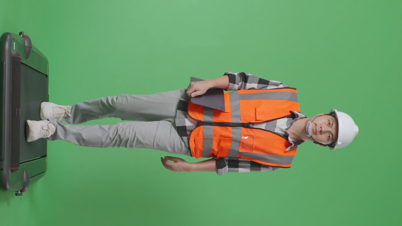 녹색 스크린 배경 스튜디오에서 는 동안 태블릿을 들고 있는 안전 헬을 입은 아시아 남성 엔지니어의 전체 몸