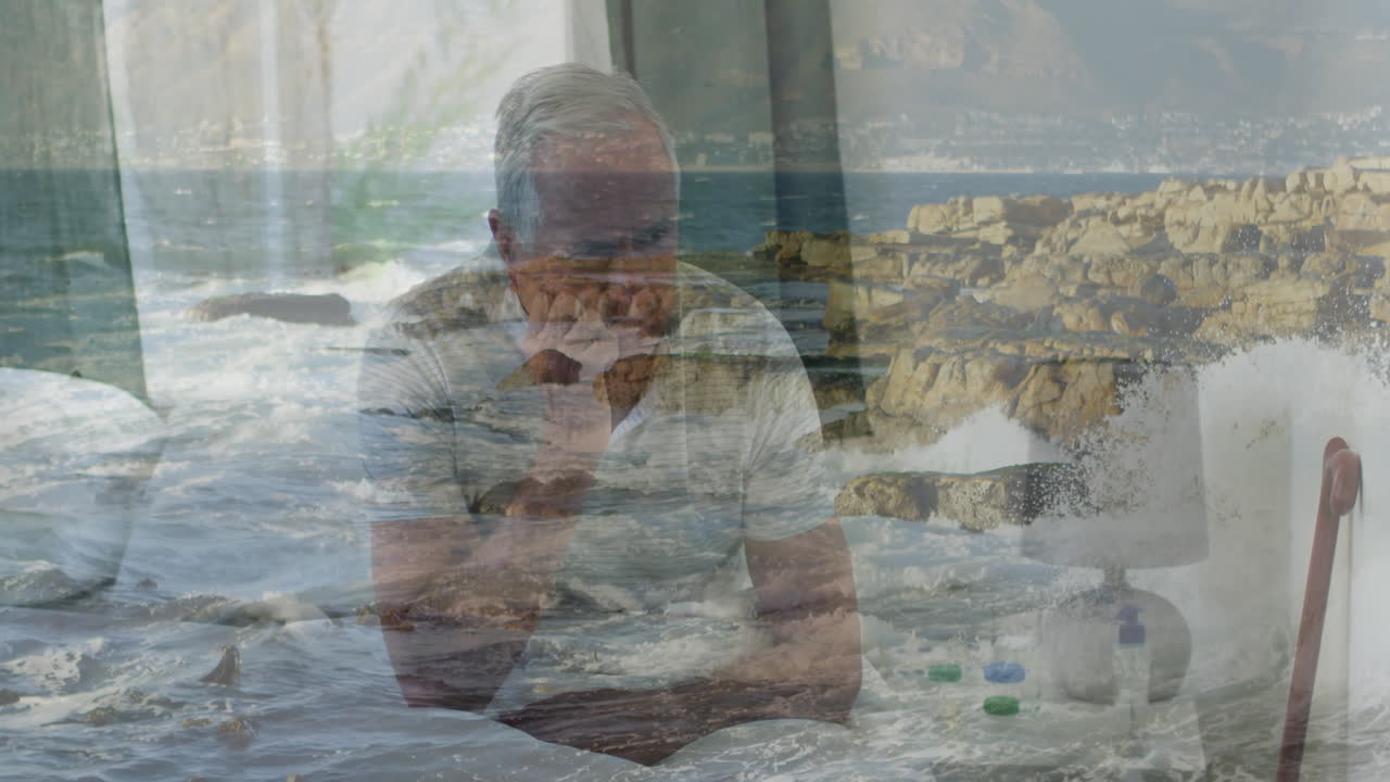 Sitting thoughtfully at home, elderly man with ocean waves animation overlay