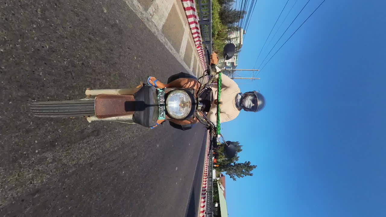 Solo Traveler Cruising Through The City Streets Of Vietnam On A Vintage Motorcycle. Backpacking Adventures In Southeast Asia; Travel, Vacation, And Tourism. Vertical Front Facing POV.