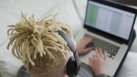 hombre albino afroamericano con rastas usando tableta y auriculares
