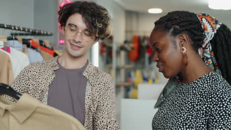 hombre joven discutiendo ropa con novia afroamericana en la tienda