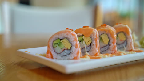 rollo de sushi de salmón con salsa en la parte superior - estilo de comida japonesa