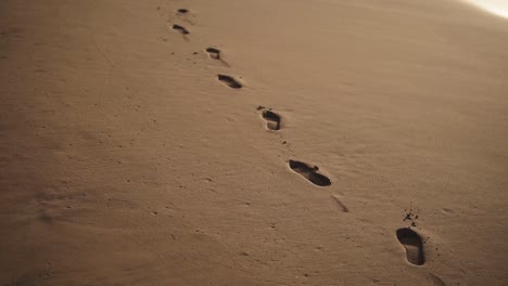Verfolgen-Sie-Nahaufnahmen-Von-Fußabdrücken-Im-Goldenen,-Nassen-Sand-Am-Strand