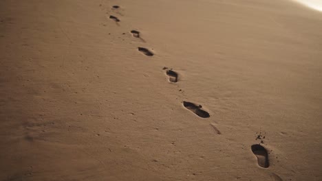 Tracking-Close-Up-footage-of-footprints-on-the-golden-wet-sand-at-beach