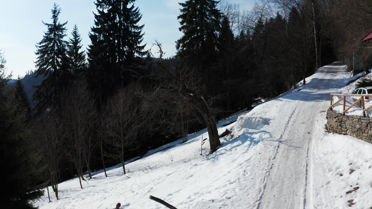 hombre montando una tabla de snowboard y cayendo después de intentar hacer un frontflip, droneshot en montañas nevadas y bosques de pinos del parque nacional krkonoce, chequia