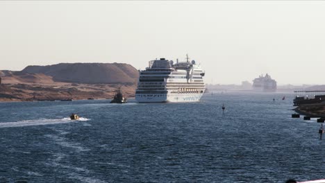 cruise ships sailing through the suez canal assisted by a tugboat on a sunny day