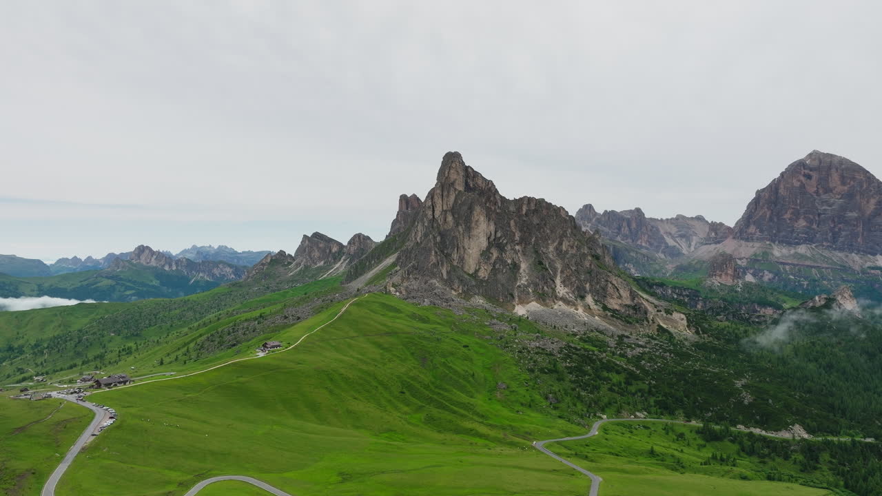 Mountain pass and rugged terrain at Giau Pass in Dolomites, aerial pullback under overcast sky