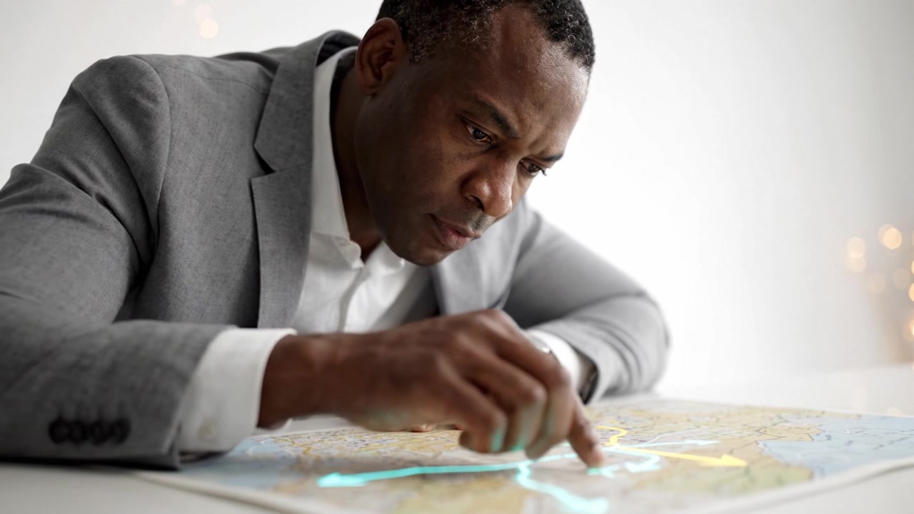 Focused Man Analyzing Map for Planning Journey with Attention to Detail and Concentration on Routes in Professional Attire