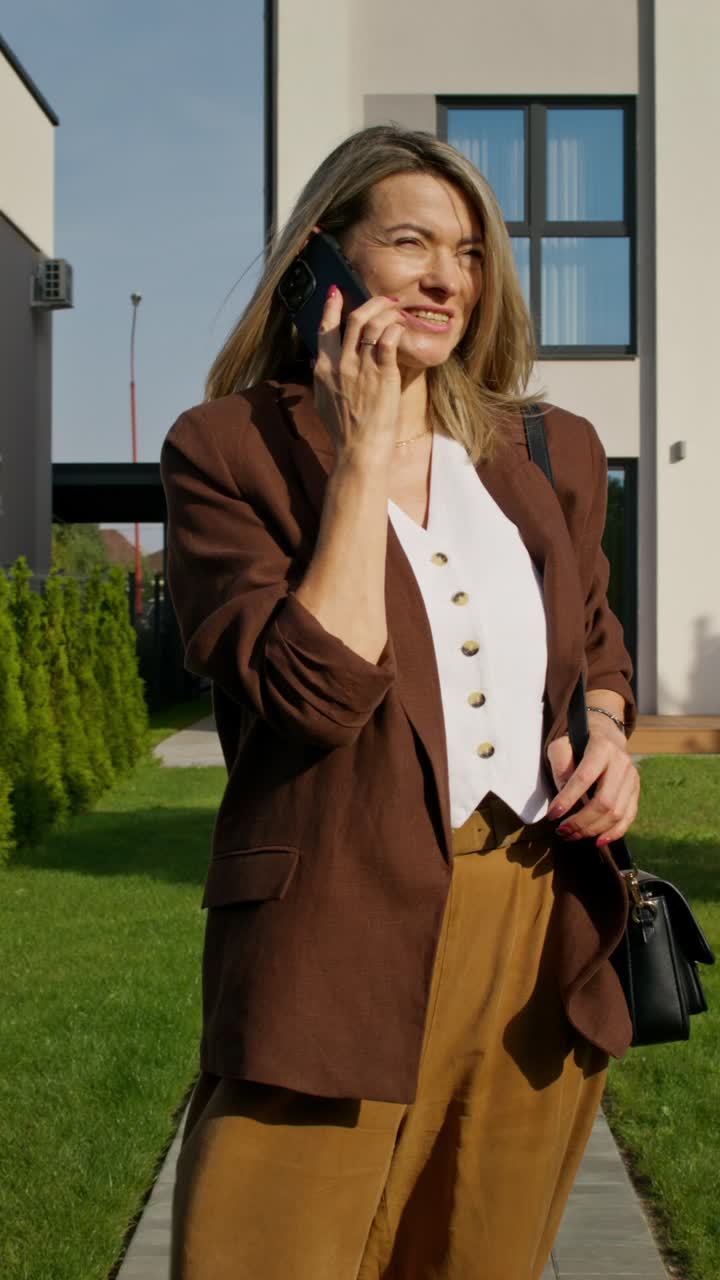 Žena telefonující před domem
