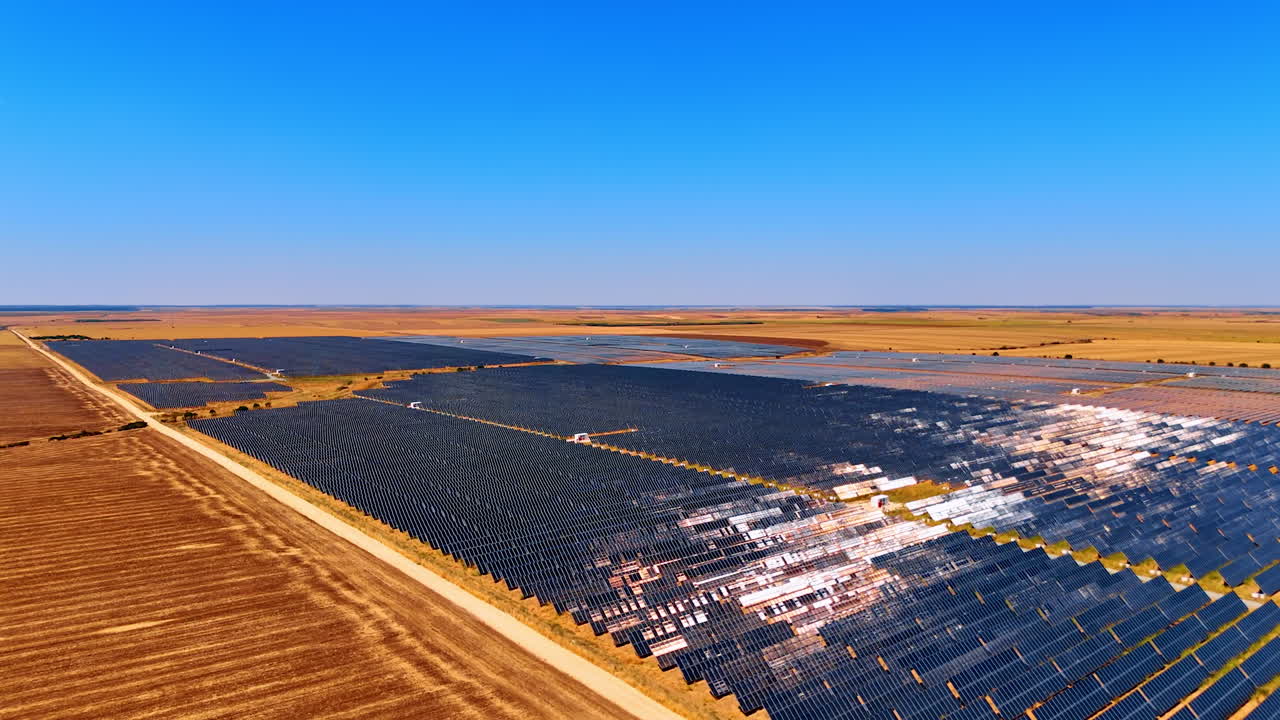 Solar power station in farmland. Aerial panorama of solar power plant fields shining under the clear blue sky in a rural landscape