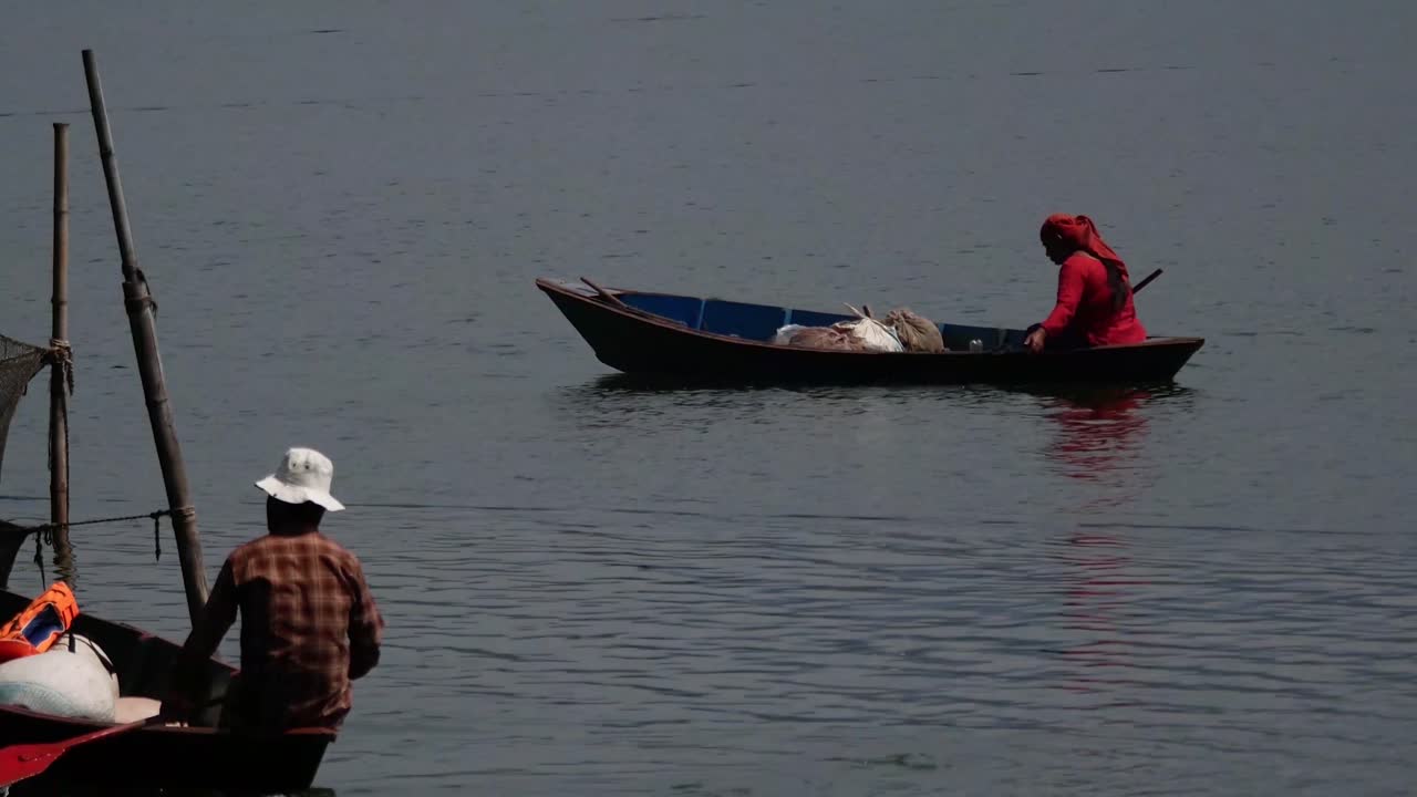 una pescadora y un hombre van a trabajar en el lago begnas de pokhara, nepal.