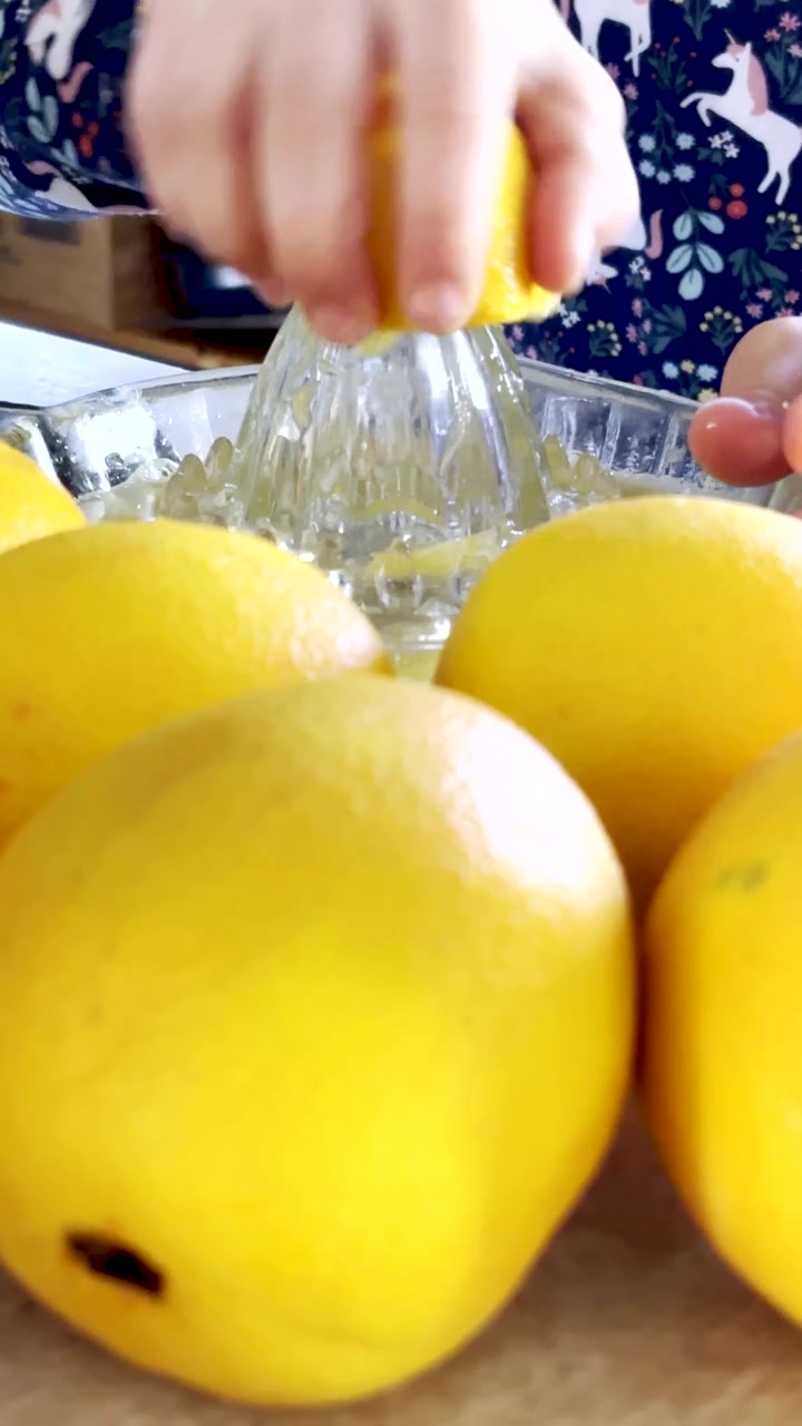 Vertical. Niño exprimiendo jugo de naranja fresco con un exprimidor de cristal, primer plano
