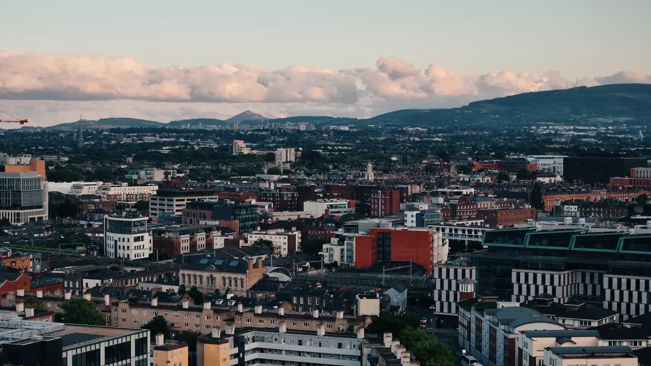 High aerial dolly right over Dublin with trains and dramatic cloudscape