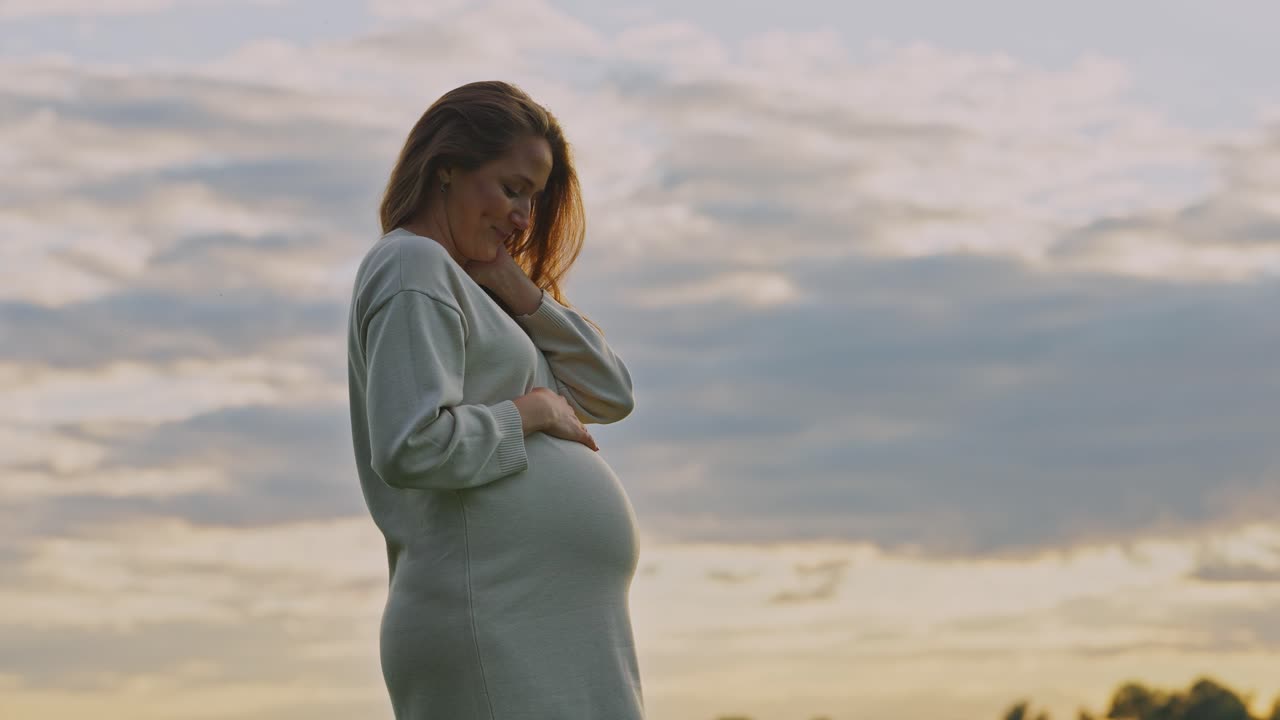 Gravid kvinne ved solnedgang