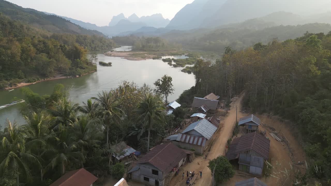 fotografía de un avión no tripulado de una carretera de tierra que conduce a través de una aldea remota en la ciudad montañosa de nong khiaw en laos, sudeste asiático