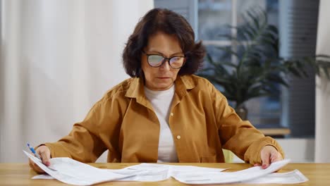 senior mature business woman holding paper bill managing finances at home