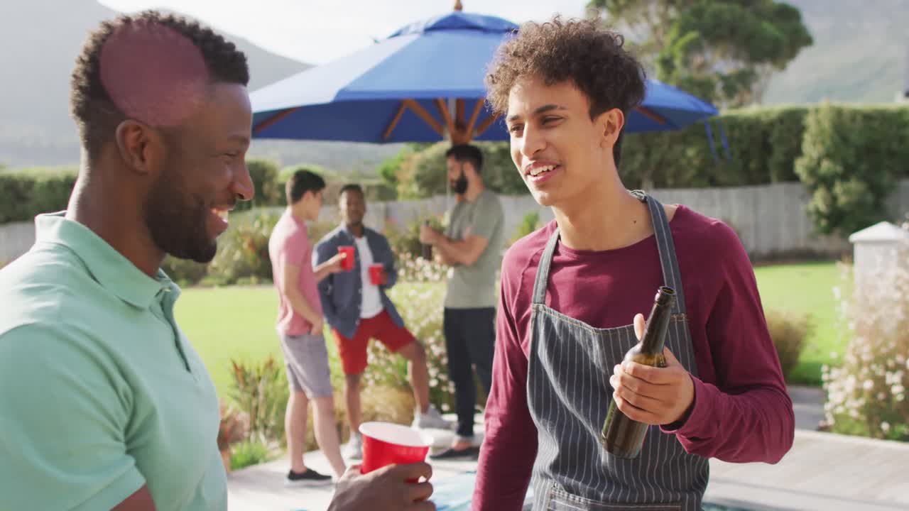 행복한 다양한 남성 친구들이  ⁇ 은 날 정원에서 맥주를 마시며 이야기하고 있습니다.