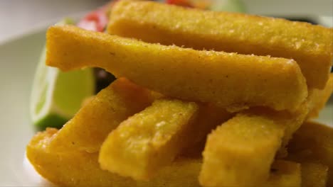 slow orbit and focus rack of plate with polenta fries, salad and lime