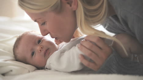 Frau-Küsst-Ein-Baby,-Das-Auf-Einem-Bett-Liegt