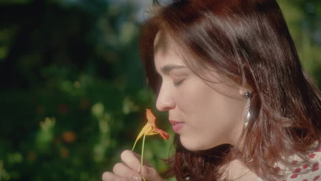 woman smells orange flower picked from the ground