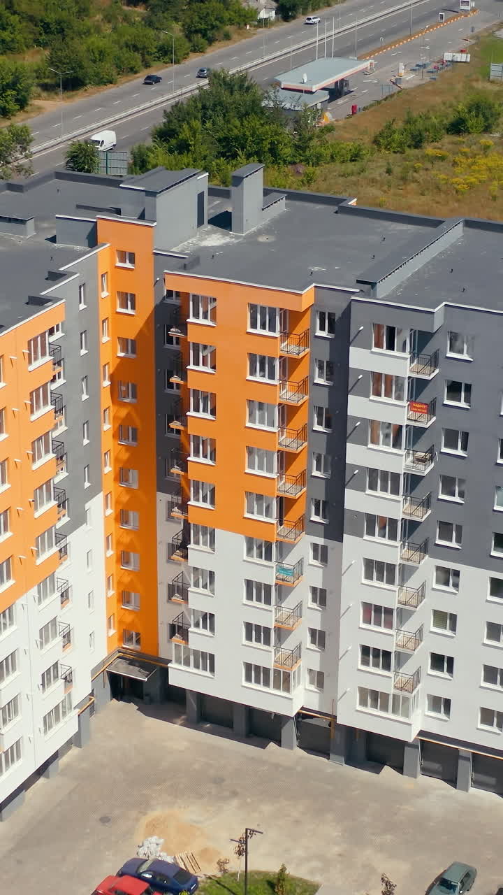 Block of flats in the city. Construction of a new apartment building. Modern high-raised building with colorful walls of residential complex. Vertical video