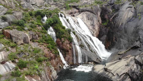 amazing view of cascada del ezaro, a beautiful waterfall in a mountainous area in a coruña, galicia, spain - aerial drone, pullback shot (slow motion)