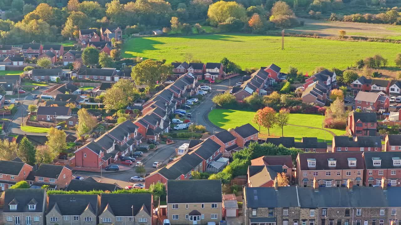 Hemingfield village showing rows of brick houses, curved streets, and surrounding green fields and woodland in South Yorkshire, England, static drone footage