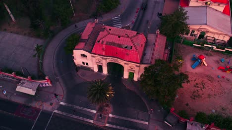 Tilt-down-aerial-orbit-of-the-entrance-arch-of-the-Hospital-Barros-Luco-in-Santiago-Chile,-sunset-light