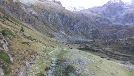 Dos-Excursionistas-En-El-Camino-De-Piedra-De-La-Cresta-De-Val-D&#39;arrouge-Que-Conduce-A-Lac-D&#39;espingo-En-Haute-garonne,-Pirineos,-Francia,-Toma-Aérea-De-Acercamiento