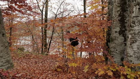 un hombre camina de derecha a izquierda con una mochila puesta durante los impresionantes colores de otoño en la temporada de otoño con hojas por todo el suelo