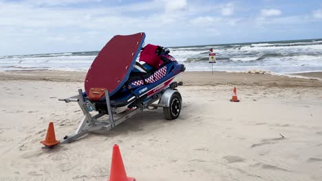 jet ski parked on sandy beach with waves