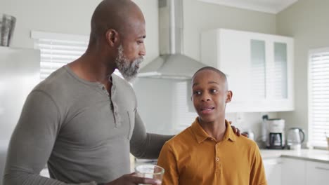 Video-of-happy-african-american-father-and-son-laughing-in-kitchen