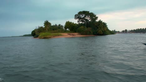 motorized canoe boat passing by next to a small island on lake volta, ada in ghana, africa