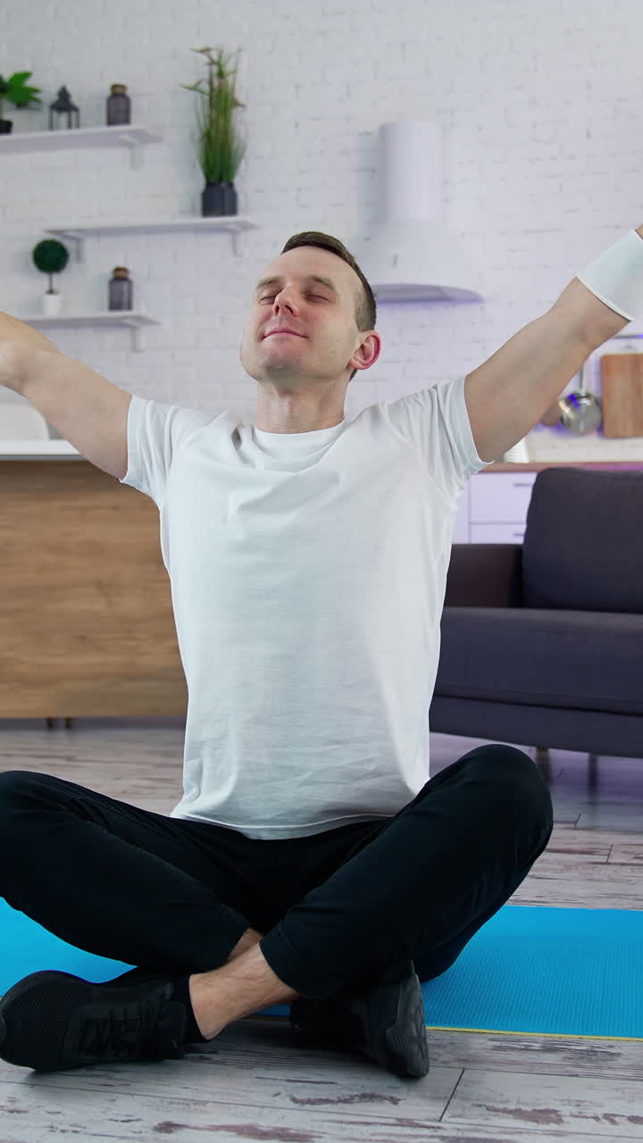 Handsome healthy man training his body in home. Strong athletic active person working out indoor. Vertical video