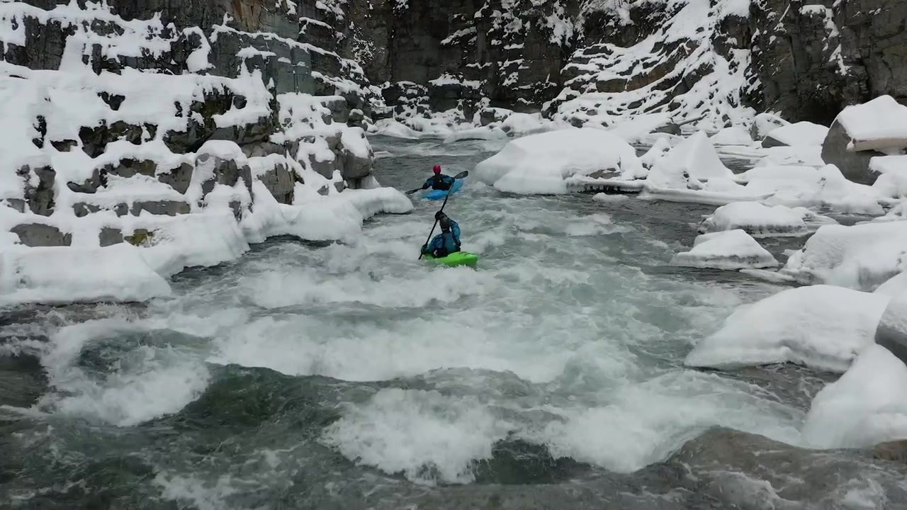 Kayakisti che remano su un fiume ghiacciato in pieno inverno, ripresi da un drone in Columbia Britannica, Canada.