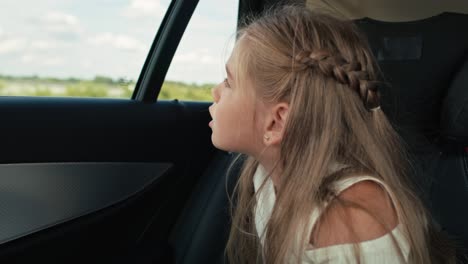 caucasian girl of 8 years looking out of the car window while car trip.