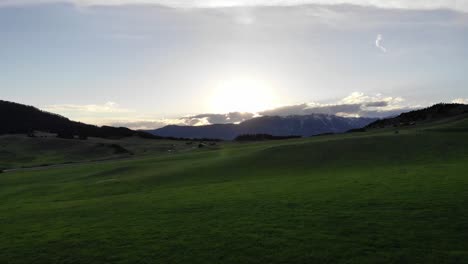 drone shot of majestic mountains surrounded by green rolling hills