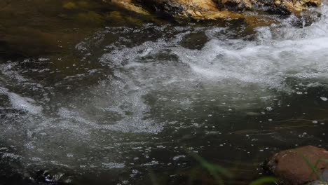 Crystal-clear-mountain-waterfall-crocodile-river-water-sparkling-and-flowing-over-rocks-and-pebbles-in-the-background-at-the-walter-sisulu-national-botanical-gardens-in-roodepoort,-South-Africa