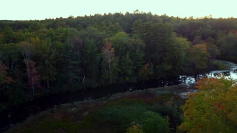 pan in shot over a small river towards a lake and forest in maine