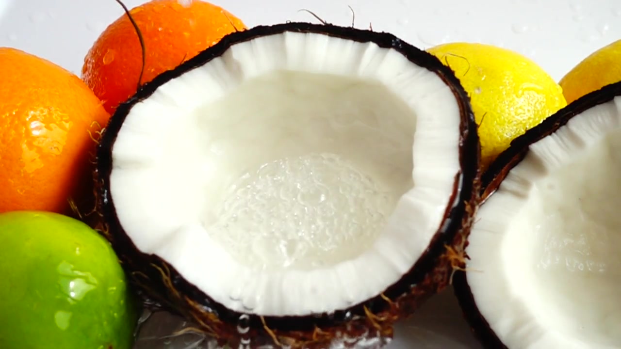 Juicy coconut flesh amid tropical fruits. Slow motion.