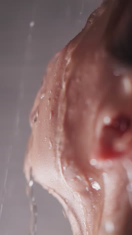 woman face in clear running water in shower cabin closeup. tranquil lady stands in warm pure sprays in home bathroom. recreation after hard day