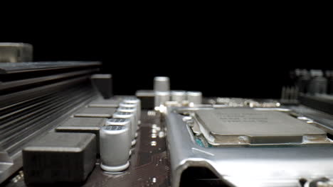foto macro de una placa base sobre un fondo negro con condensadores, cpu y transistores de primer plano