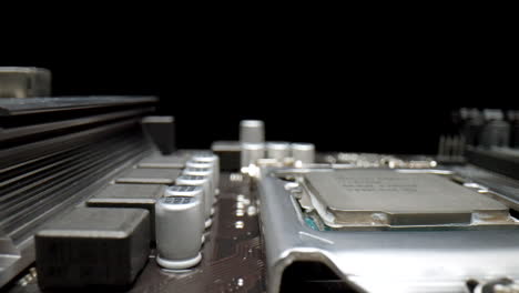 macro shot of a motherboard on a black background with capacitors, cpu and transistors close-up