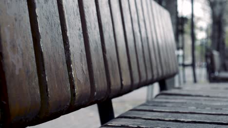 empty wooden bench in a small town square with people walking by