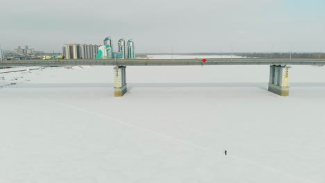 Lange-Brücke-Mit-Fahrenden-Autos-über-Den-Zugefrorenen-Fluss